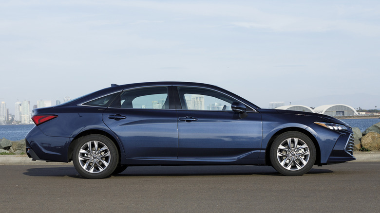 Side view of blue Toyota Avalon parked in front of harbor.