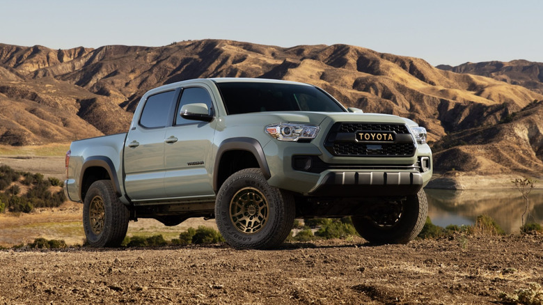 Front 3/4 view of gray Toyota Tacoma parked in front of lake.
