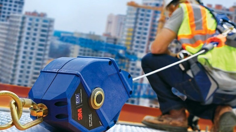 Person using fall protection anchor atop a roof construction site