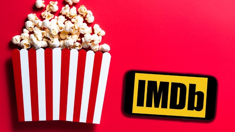 A bucket of popcorn next to a phone showing IMDb