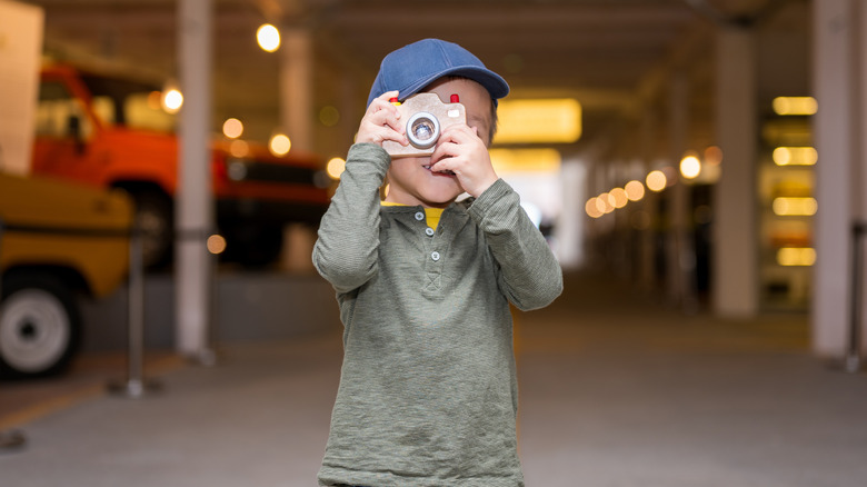 A boy snapping a photo at a car museum.