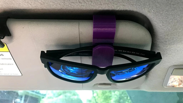 Sunglasses hanging on a vehicle sun visor on a purple 3D printed clip