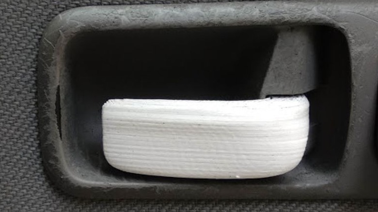White 3D printed door handle replacement affixed to black plastic on a Volkswagen