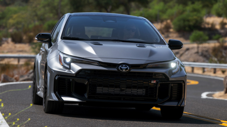 Front view of 2026 Toyota GR Corolla on winding road in forested area