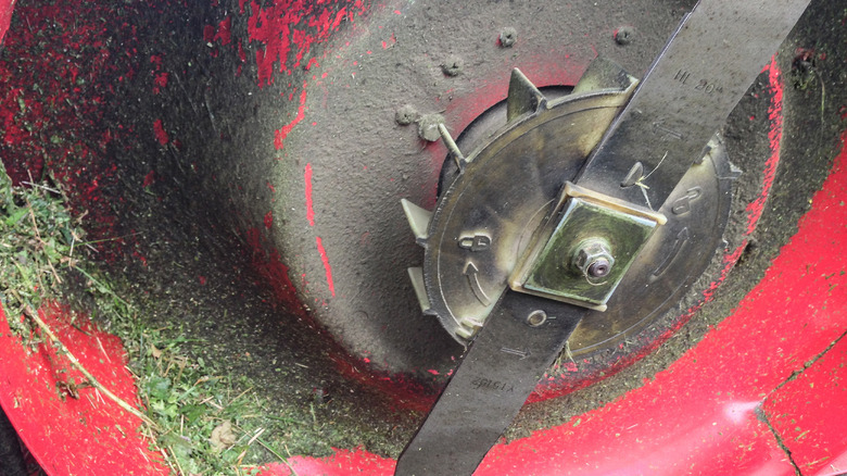 A lawnmower flipped up so you can see the mower blade.