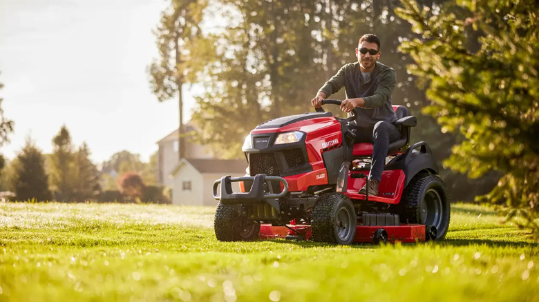 A man riding a Craftsman riding mower in the morning sun.