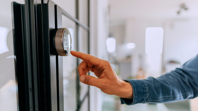Hand reaching toward smart thermostat