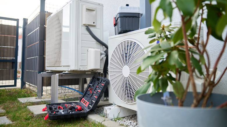 Heat pump units outside a residence with an open toolbox on the ground