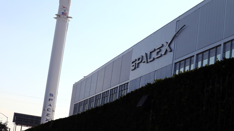 An industrial building with the SpaceX logo prominently displayed in silver on the top
