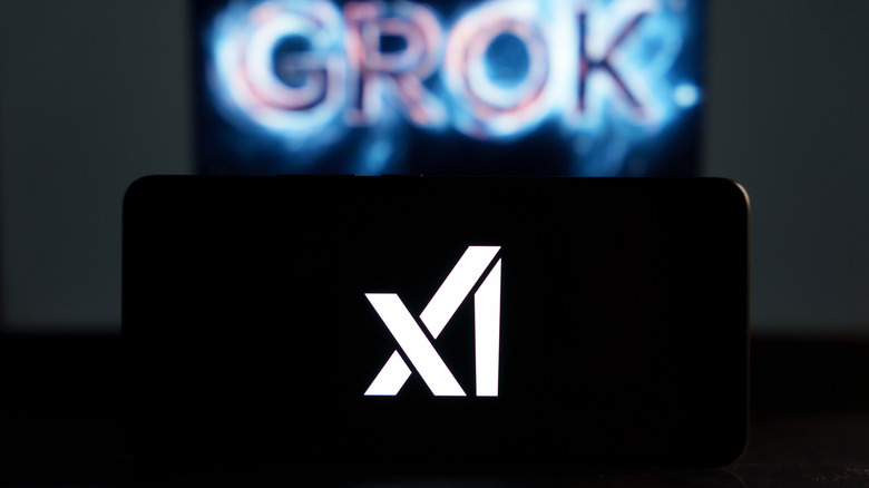 A phone with the X.AI logo in front of a wall that says "GROK" in the background