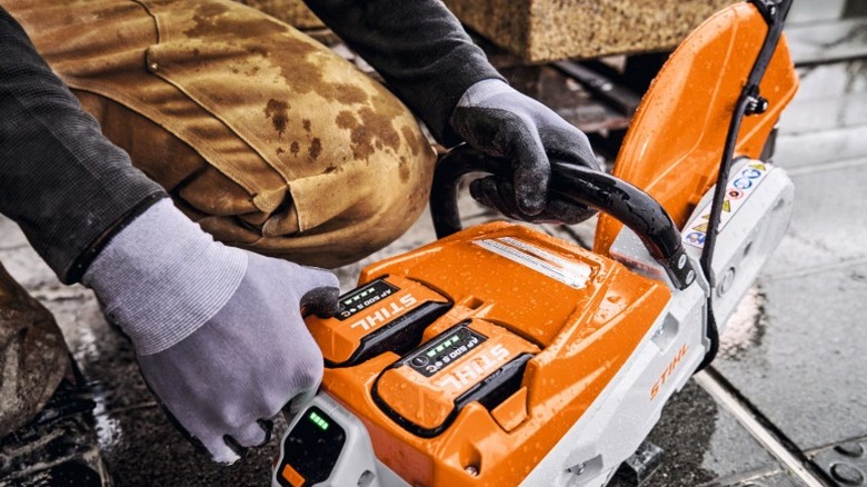 Gloved hands holding a Stihl TSA 500 cut-off machine in rainy weather
