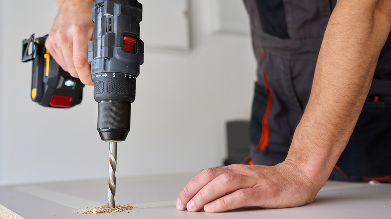 person drilling a hole with cordless drill