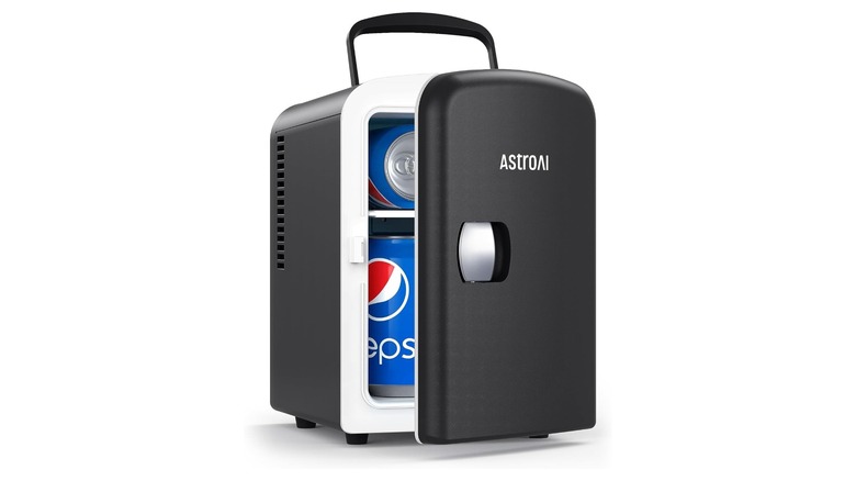 Black mini refrigerator with door ajar showing cans of soda