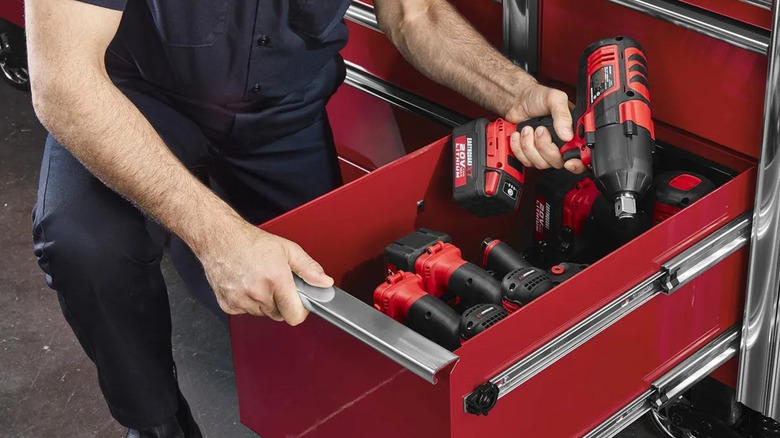 A man pulling power tools out of a bright red toolbox