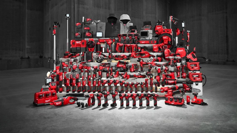 Various Milwaukee tools on a stand against a gray concrete-like background