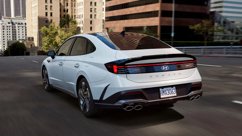 A white Hyundai Sonata driving on a road.