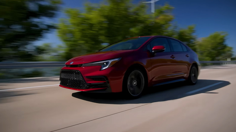 A red Toyota Corolla driving down a highway