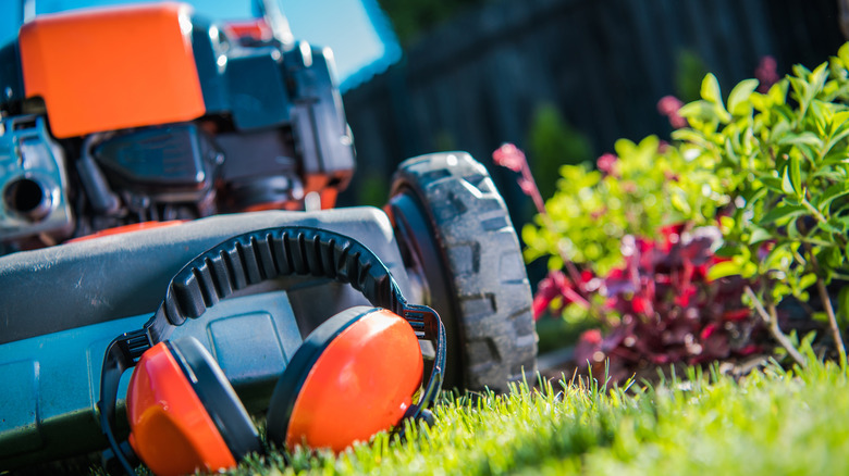 Headphones laying against the underside of a lawn mower.