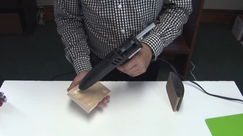A person applying glue to the back of a wood piece to secure it