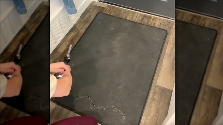 A person applying glue to the underside of a carpet with a glue gun