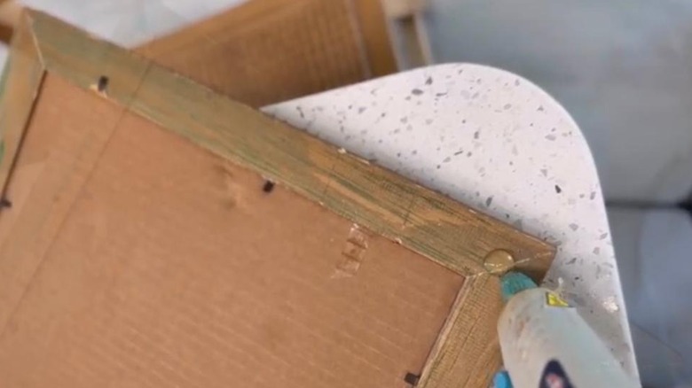 A blob of glue being applied to the edge of a picture frame