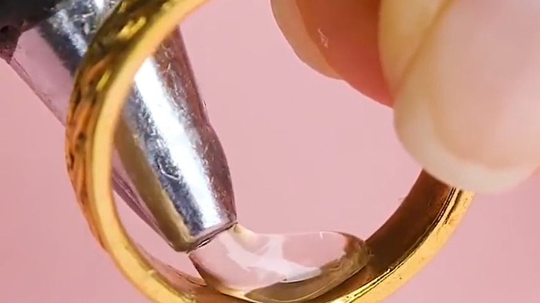 A person adding blobs of glue to the inside of a ring