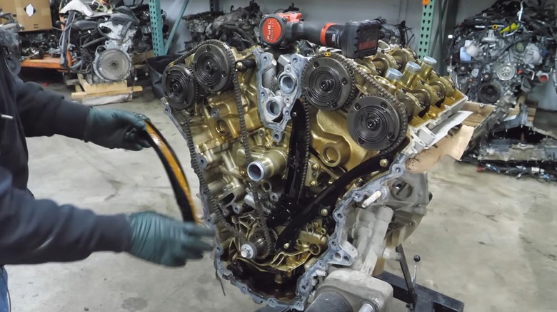 A mechanic working on a bare Ford GT's 3.5L EcoBoost V6 engine.