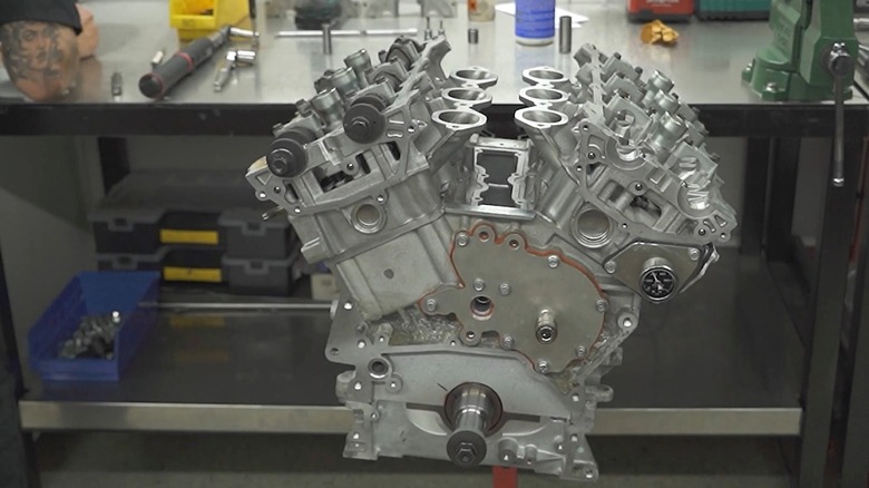 A Nissan VR38DETT V6 engine block sitting on a workshop bench.