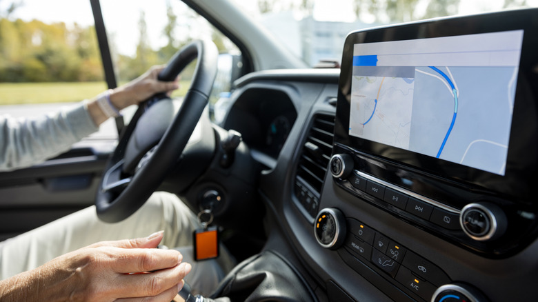 An elderly person with both hands on a steering wheel in a car.