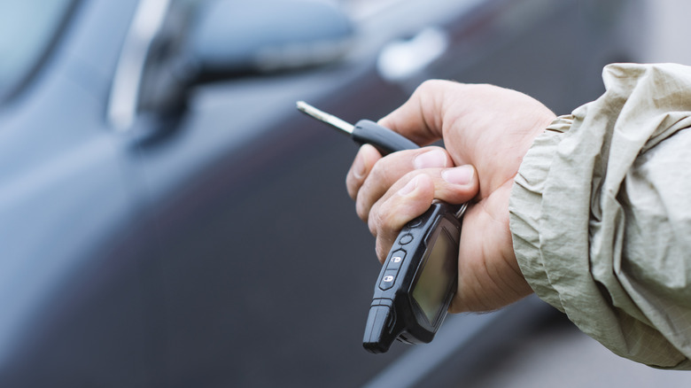 A person pressing a key fob to open a car.