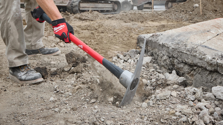 A man digging in the dirt with a Milwaukee brand mattock