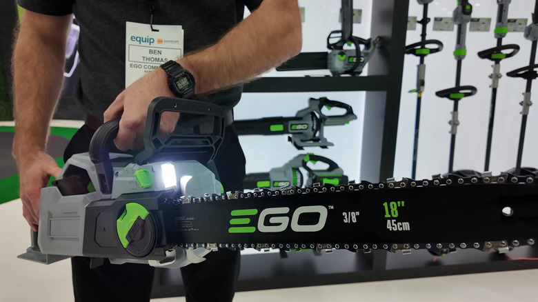 A person holding the EGO Power+ 18" Chain Saw, with other power tools in the background