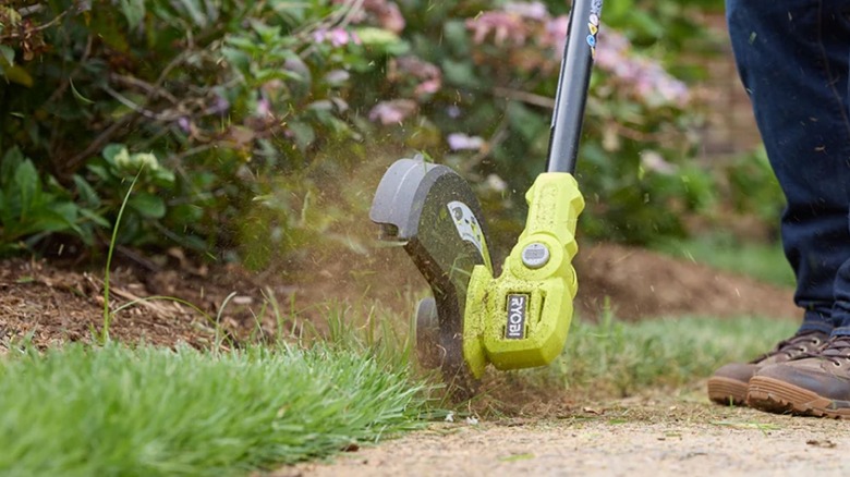 Person using Ryobi PCLST02K tool to edge sidewalk