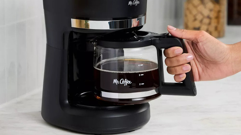 Hand removing Mr. Coffee pot from coffee maker