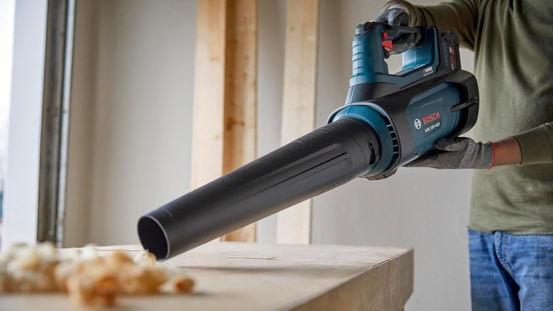 A person outside of the frame directs a Bosch blower on a table