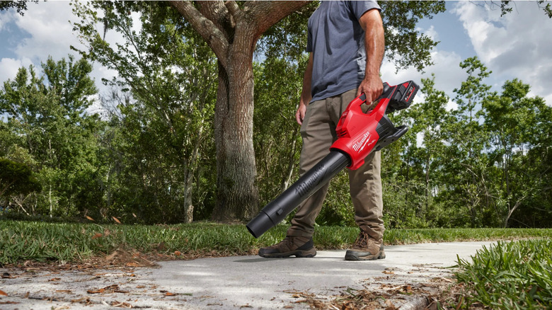 A man uses a red Milwaukee blower on a lane.