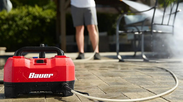 A man pressure washing patio furniture with a Bauer pressure washer