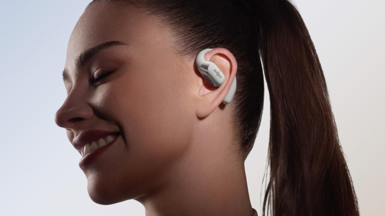 Woman with ponytail wearing white Shokz OpenFit 2+.