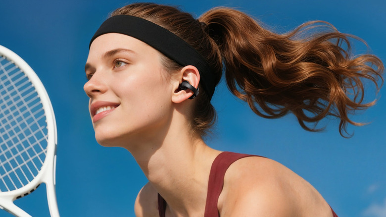 Woman playing tennis while wearing Soundcore C50i.