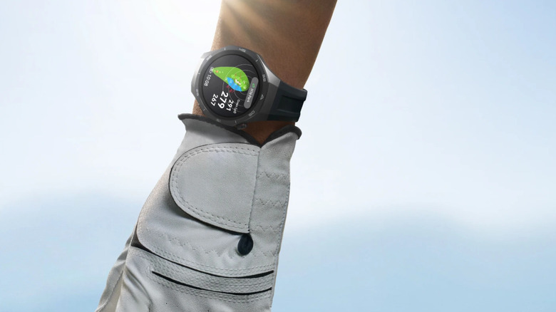 A gloved hand picking up a golf ball while wearing a Huawei Watch GT 5 Pro.