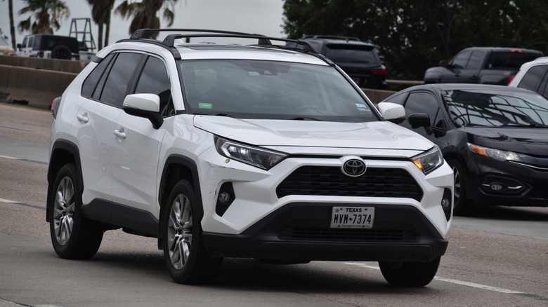 White Toyota RAV4 driving on a multi-lane highway with vehicles to the right of it