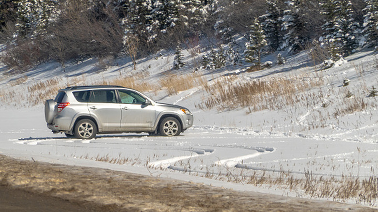 Silver Toyota RAV4 parked in snow with yellow grass showing through the snow