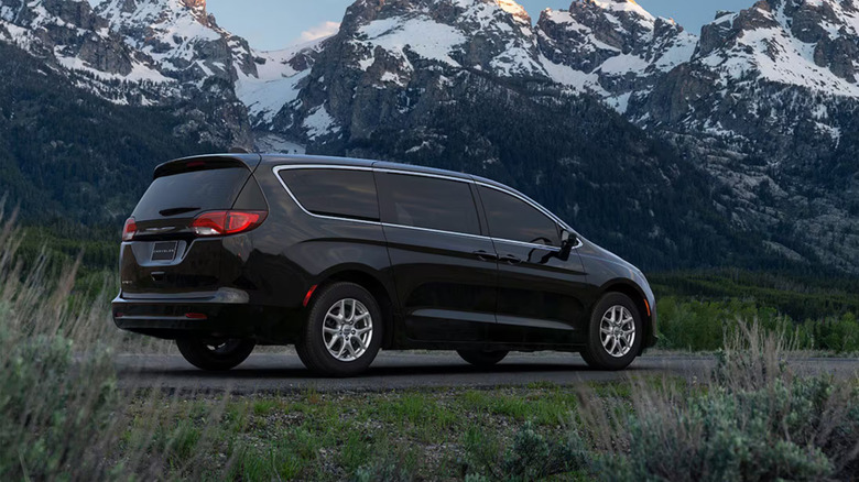 A black Chrysler Voyager on a road with mountains in its view