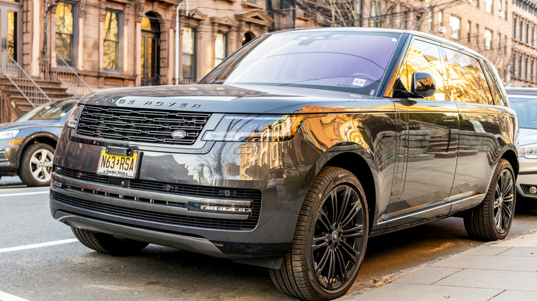 A silver Land Rover Range Rover parked by a curb in an urban residential area.