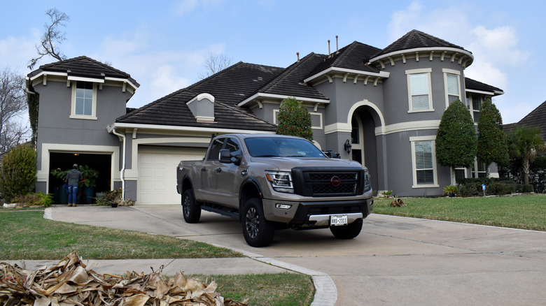 A mud brown Nissan Titan in a residential driveway