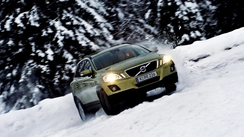 A Green 2011 Volvo XC60 offroading in the snow