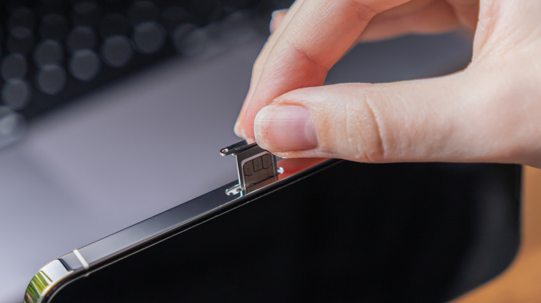 Picture of person sliding the tray of a SIM card slot out.