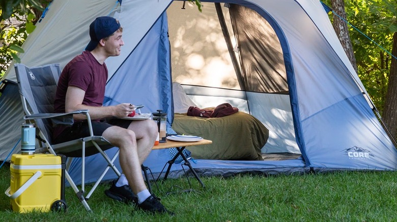 Person outside blue six-person tent