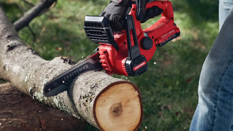 A person using the Craftsman V20 Chainsaw to cut a log