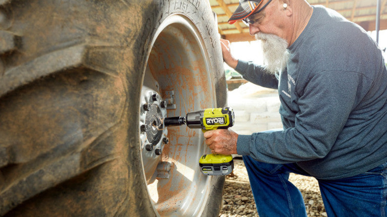 A person using the Ryobi High Torque Impact Wrench on a massive vehicle wheel.